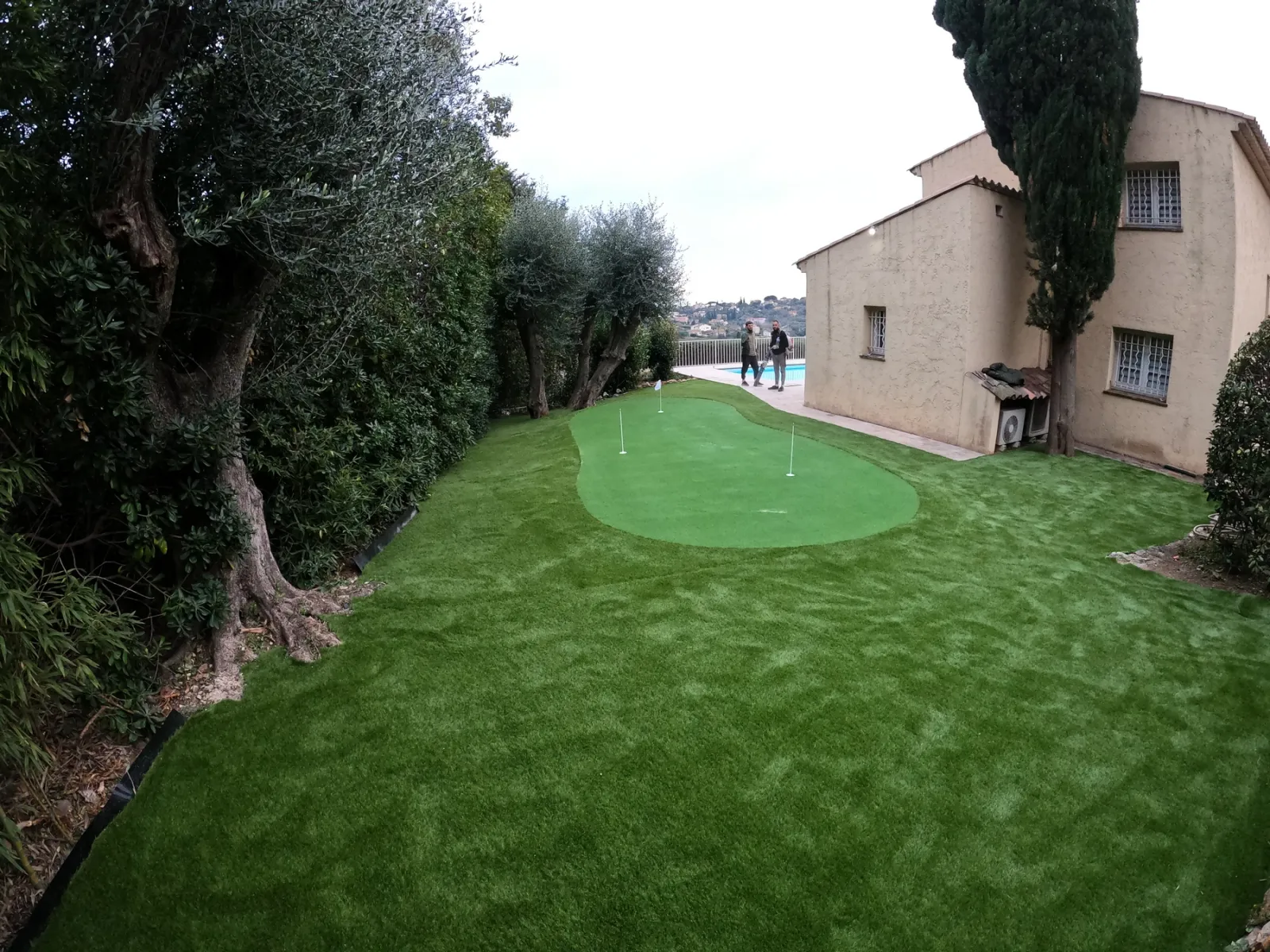 Vue d'ensemble après réalisation, 40 m² de putting green à deux trous et 110 m² de gazon synthétique Riviera 35 mm, piscine en arrière-plan.