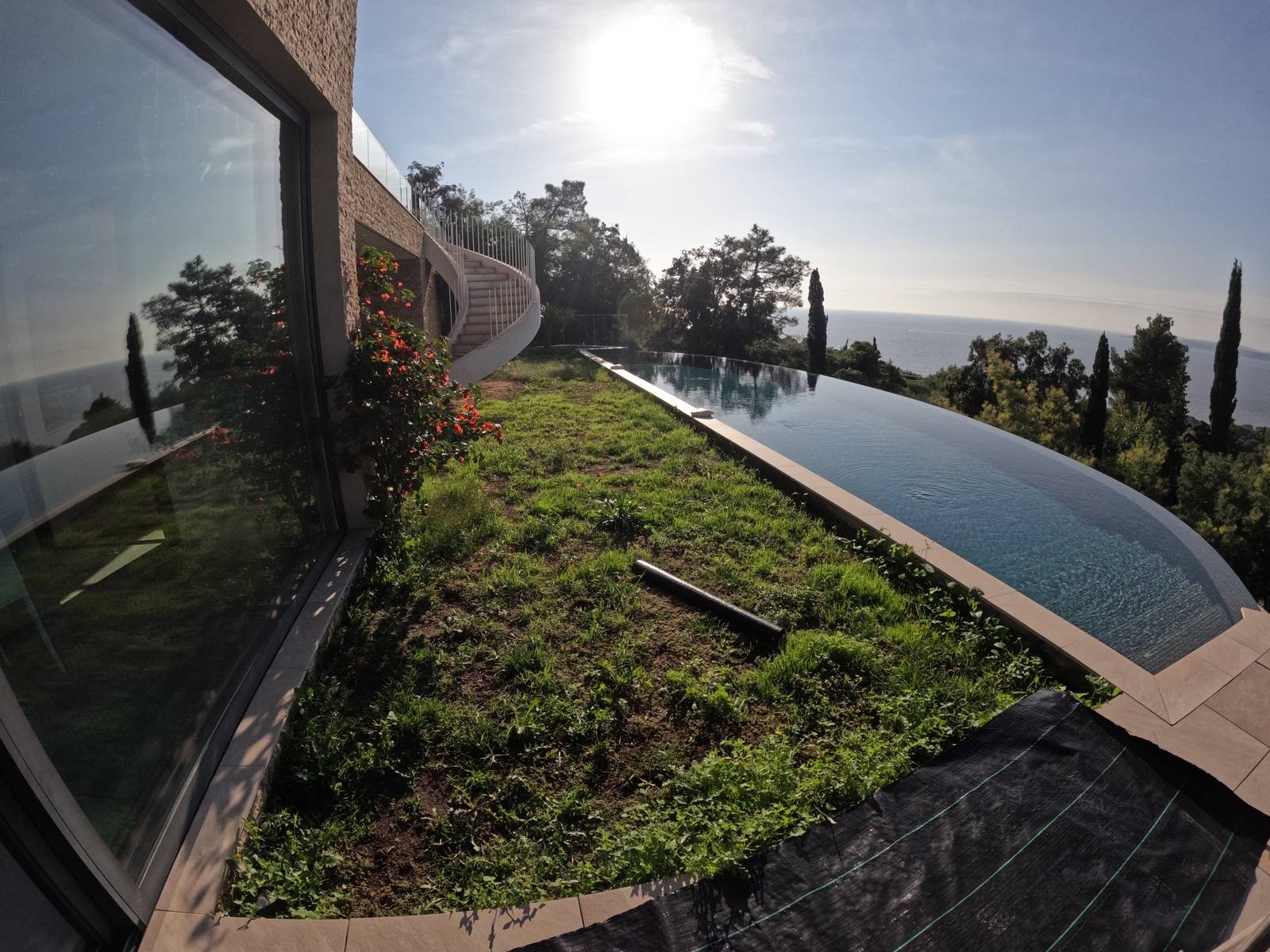 Installation de gazon synthétique AZUR devant une piscine à débordement aux Issambres, près de Fréjus