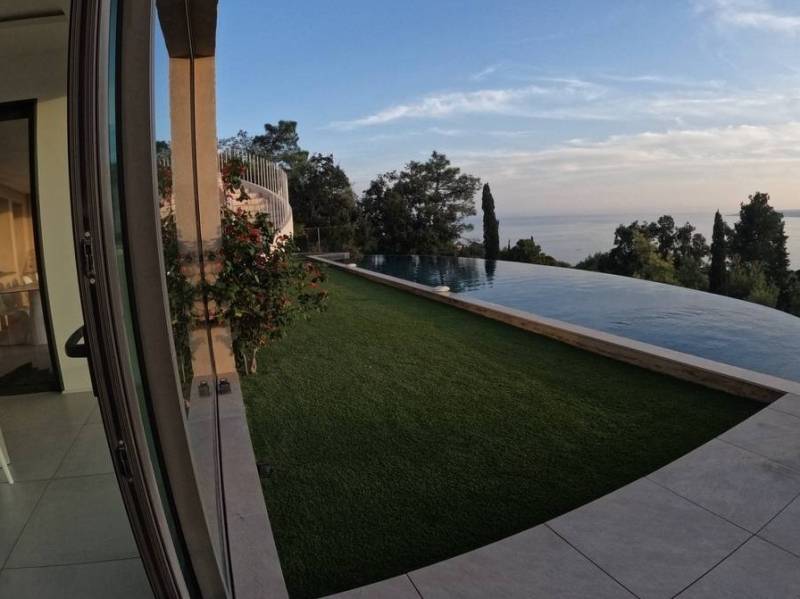 Installation de gazon synthétique AZUR devant une piscine à débordement aux Issambres, près de Fréjus