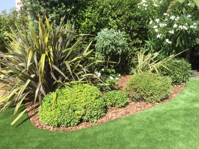 Intégration du gazon synthétique autour des massifs végétaux — détail d'un jardin à Nice en LUXE 45 mm