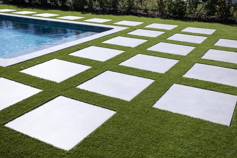 Aménagement d'un tour de piscine et jardin en gazon synthétique haute qualité à La Roquette (06) avec utilisation de dalles de carreau rectangulaires grises